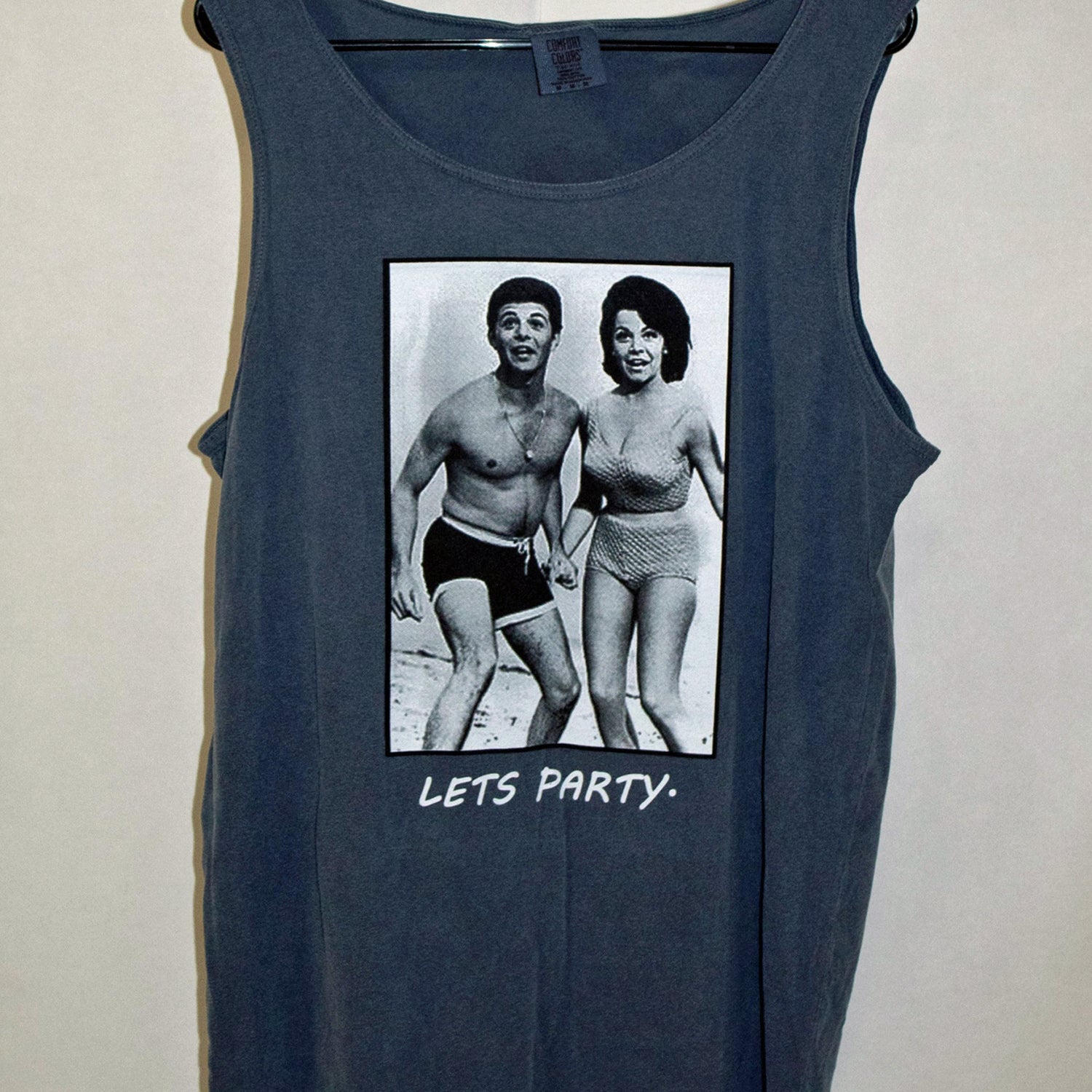 The 'BIRTHDAY PARTY' Tank Top Shirt (Fried Navy Blue in color) is sure to beat the heat this summer while layin' the vibe out pretty clearly:  Let's flippin' party!  This stylish, soft, and comfy Tank Top Shirt is slightly wider than your ordinary tee; it's a loose fit and extremely comfy on those hot summer days.  In length, it runs similar to a normal T Shirt, if anything 1/2" shorter.  It's got that 90's tank style going strong! Designed by No Wave NC